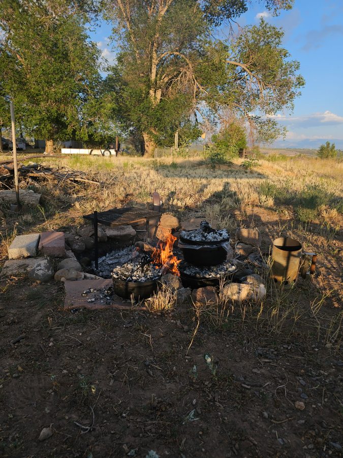 Dutch oven campfire cooking at golden hour under cottonwood trees